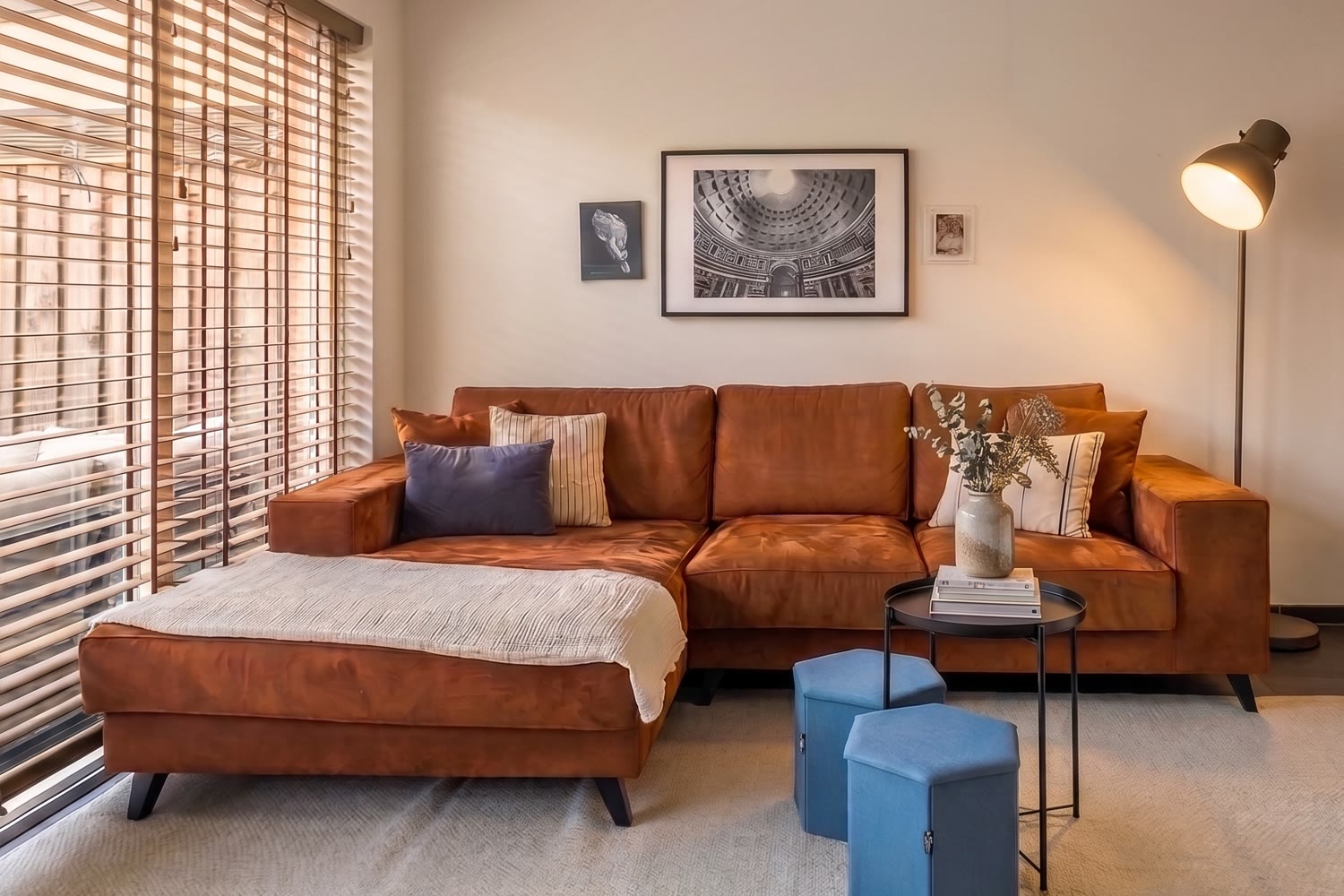 Sala com sofá terracota, manta e luz quente ao fim da tarde